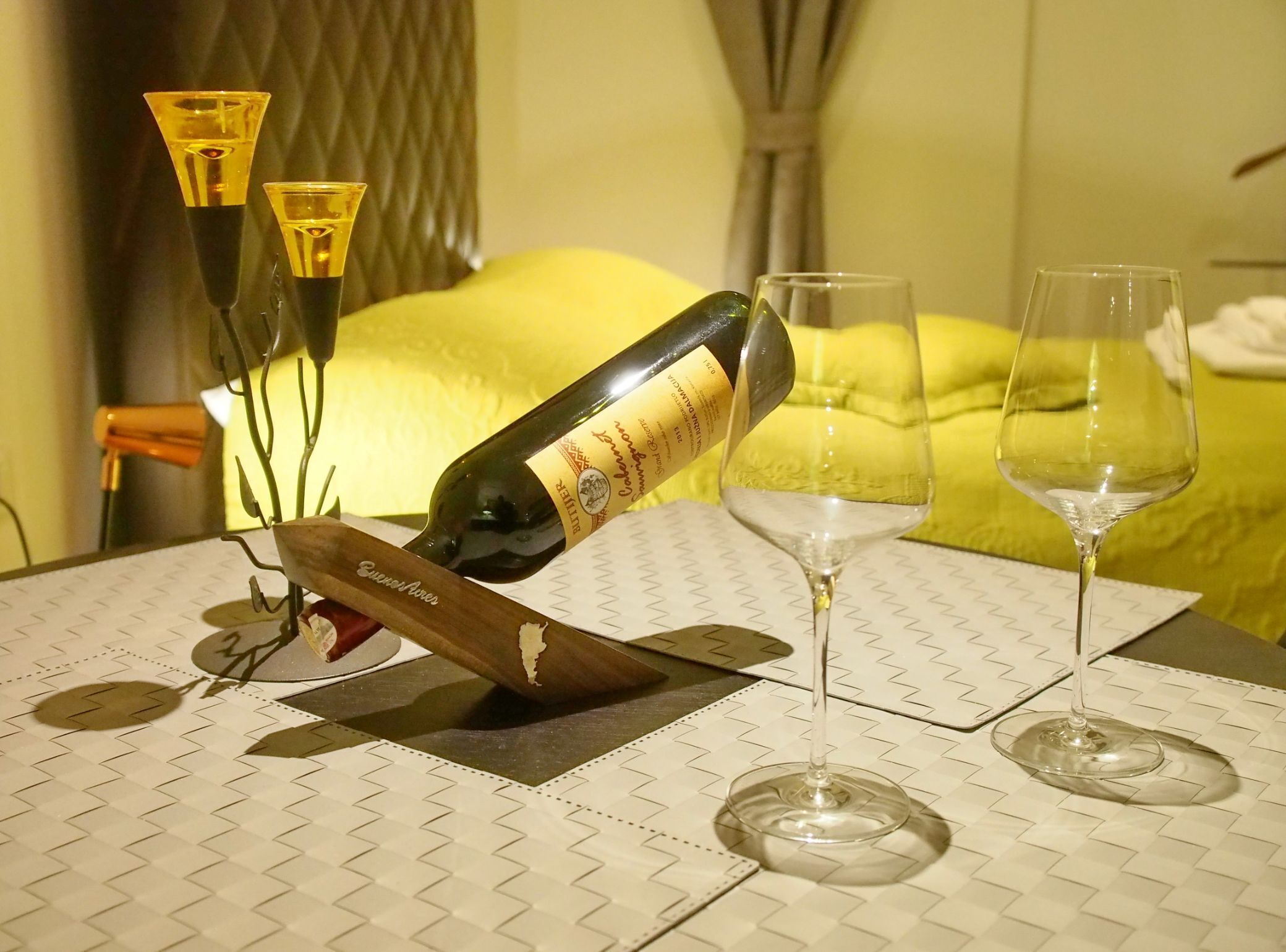 A table with a bottle of wine, two glasses, and a decorative candle holder.