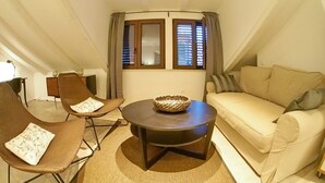 A cozy living room with a round table, two brown chairs, a beige sofa, and a window with curtains. - Luxury Style Apartments (Dubrovnik)