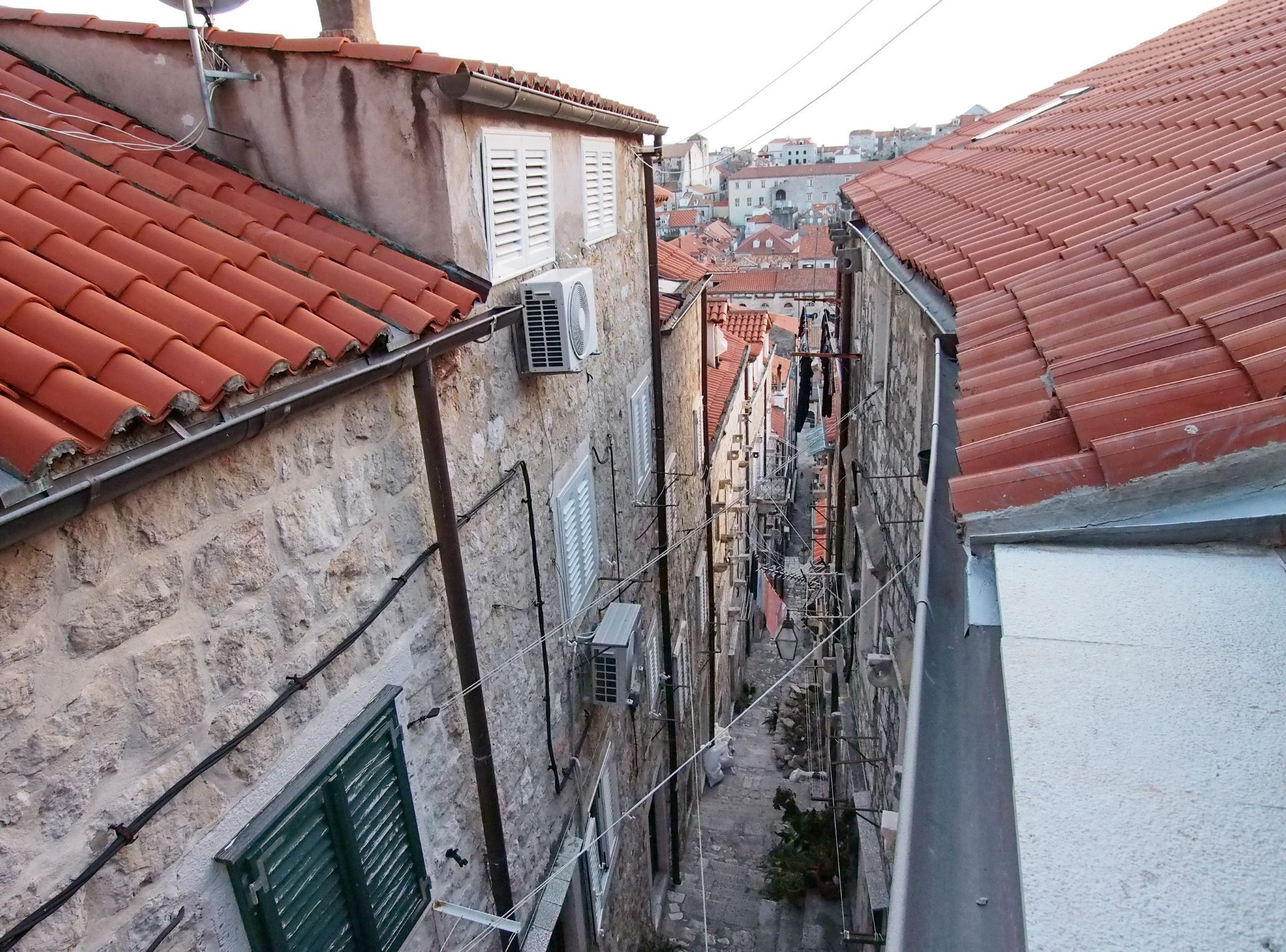 Un estrecho callejón entre edificios con tejados rojos y paredes de piedra.
