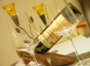 Una botella de vino con etiqueta, colocada en una copa con base de madera.
