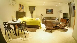 A hotel room with a bed, a dining table with chairs, a sofa, a TV, and a painting on the wall. - Luxury Style Apartments (Dubrovnik)
