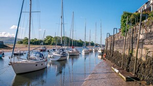 A marina with multiple sailboats docked along a stone quay.