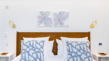 A neatly made bed with patterned pillows, a wooden headboard, and two wall-mounted lamps.