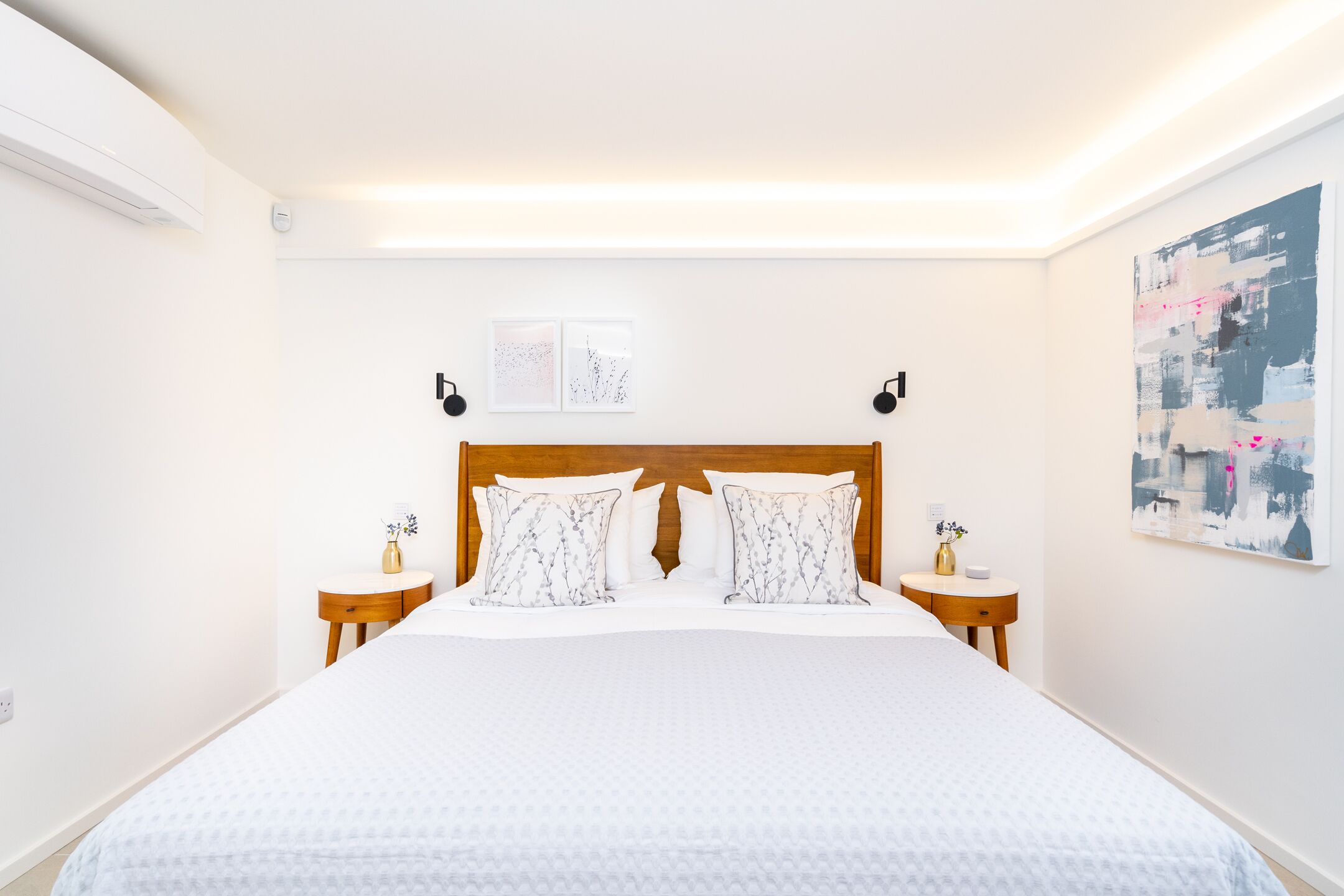 A neatly arranged hotel room with a large bed, two bedside tables, and a wall-mounted artwork.