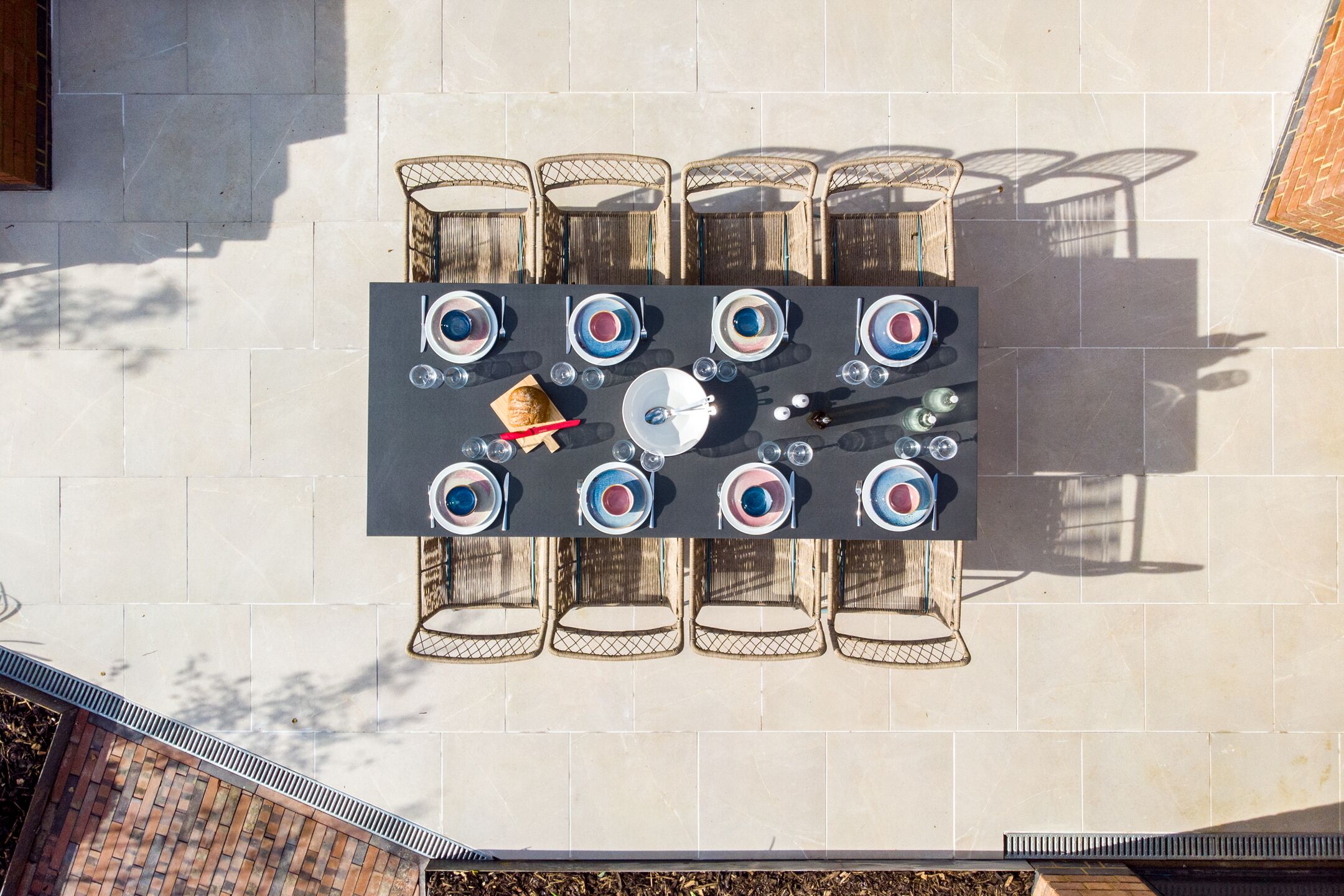 A top-down view of a dining area with a rectangular table surrounded by six chairs, a basket, and various dining utensils.