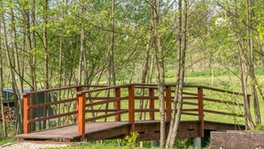A wooden bridge in a wooded area with a gravel path in the foreground.
