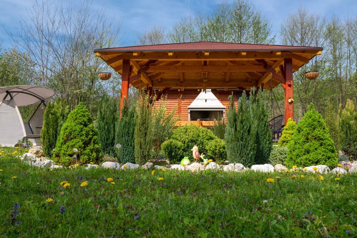 Eine Holzhütte mit einer Veranda, umgeben von Grün und Bäumen.