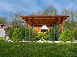 A wooden cabin with a covered patio, surrounded by greenery and trees. - Robinzonski Kamp Hofman (Gornji Kneginec)