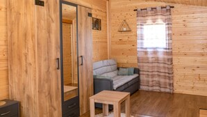 A wooden cabin interior with a sofa, a small table, and a wardrobe.