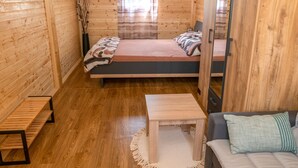 A cozy wooden cabin room with a bed, a small table, and a bench.