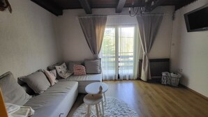 Uma sala de estar com sofá, mesa redonda, tapete de pele e janela com cortinas.