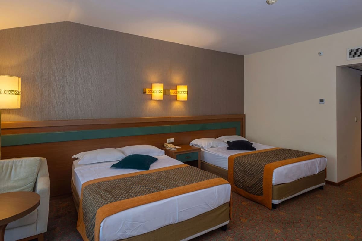 A hotel room with two single beds, a desk, and a chair.