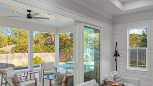 A covered patio area with a pool, white furniture, and a ceiling fan. - Close to 2 Beach Accesses on 30A! Golf Cart, Large Private Pool and Hot Tub (Santa Rosa Beach)