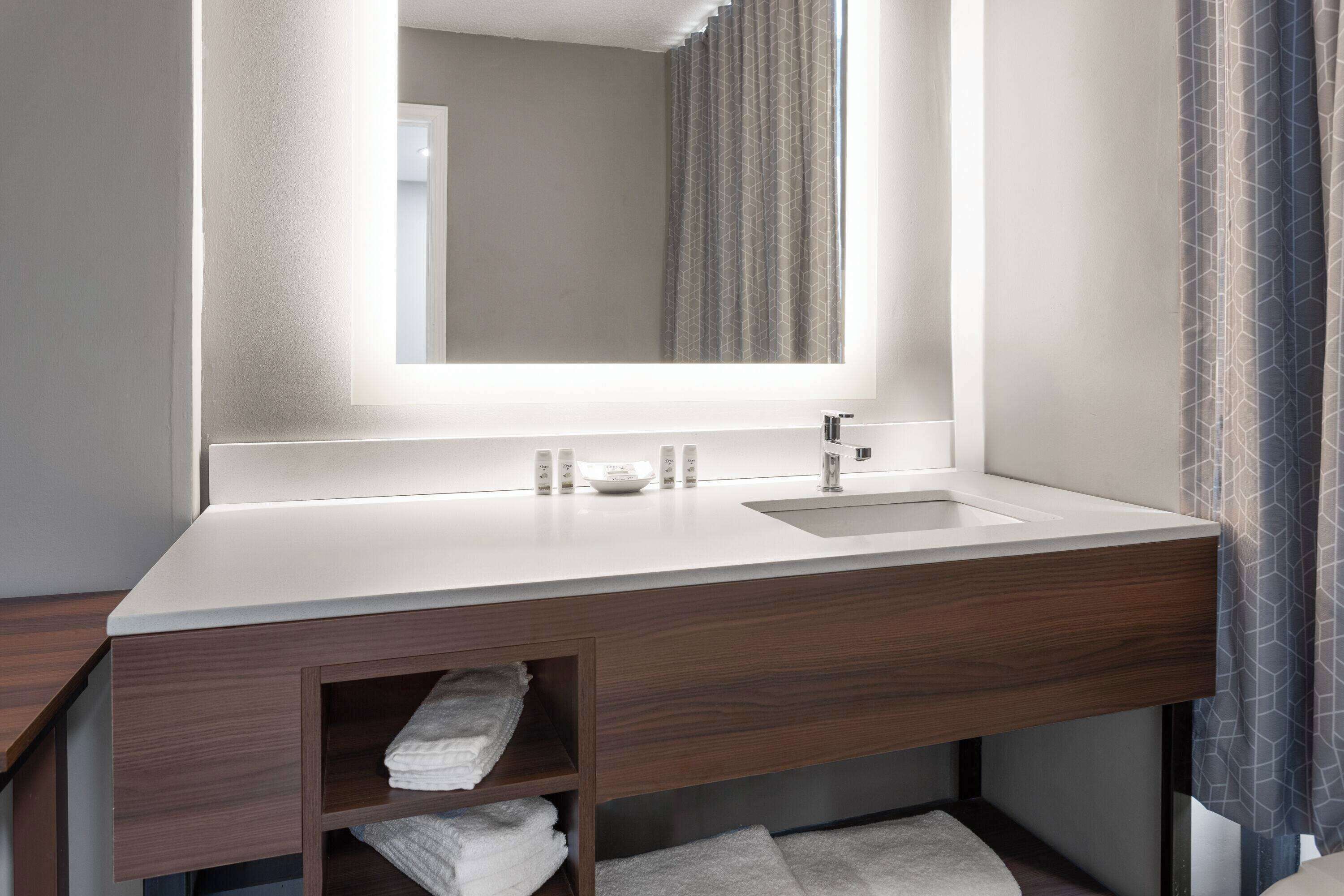 Un bagno moderno con un ampio specchio, un lavandino bianco e mobili in legno.