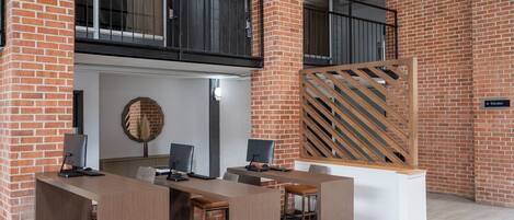 Un espacio de oficina moderno con pared de ladrillo, un escritorio de madera y una computadora.