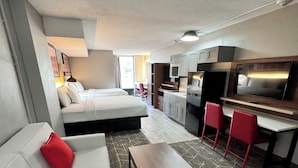 Una habitación de hotel moderna con sofá, una mesita, kitchenette y zona de comedor.
