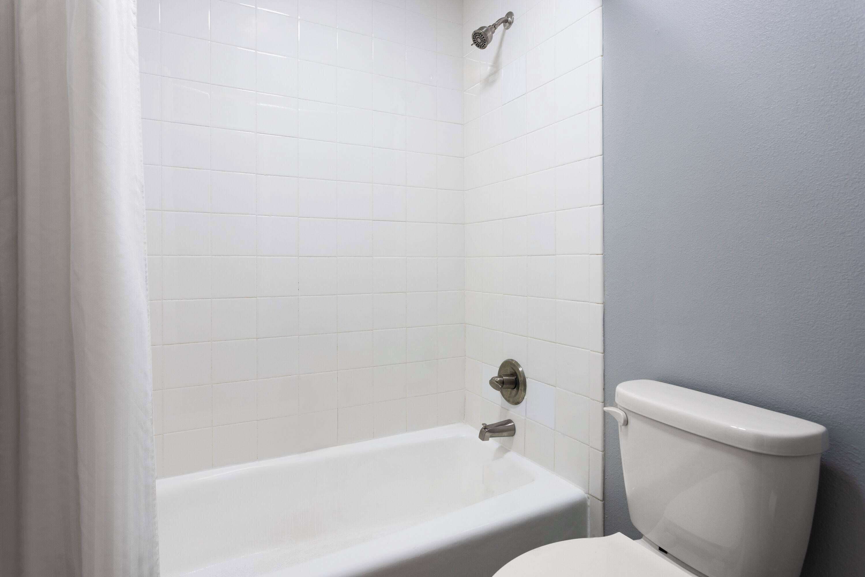 A bathroom with a white bathtub, a toilet, and a showerhead.
