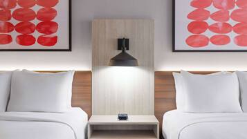 A hotel room with two beds, a nightstand, and a wall-mounted lamp.