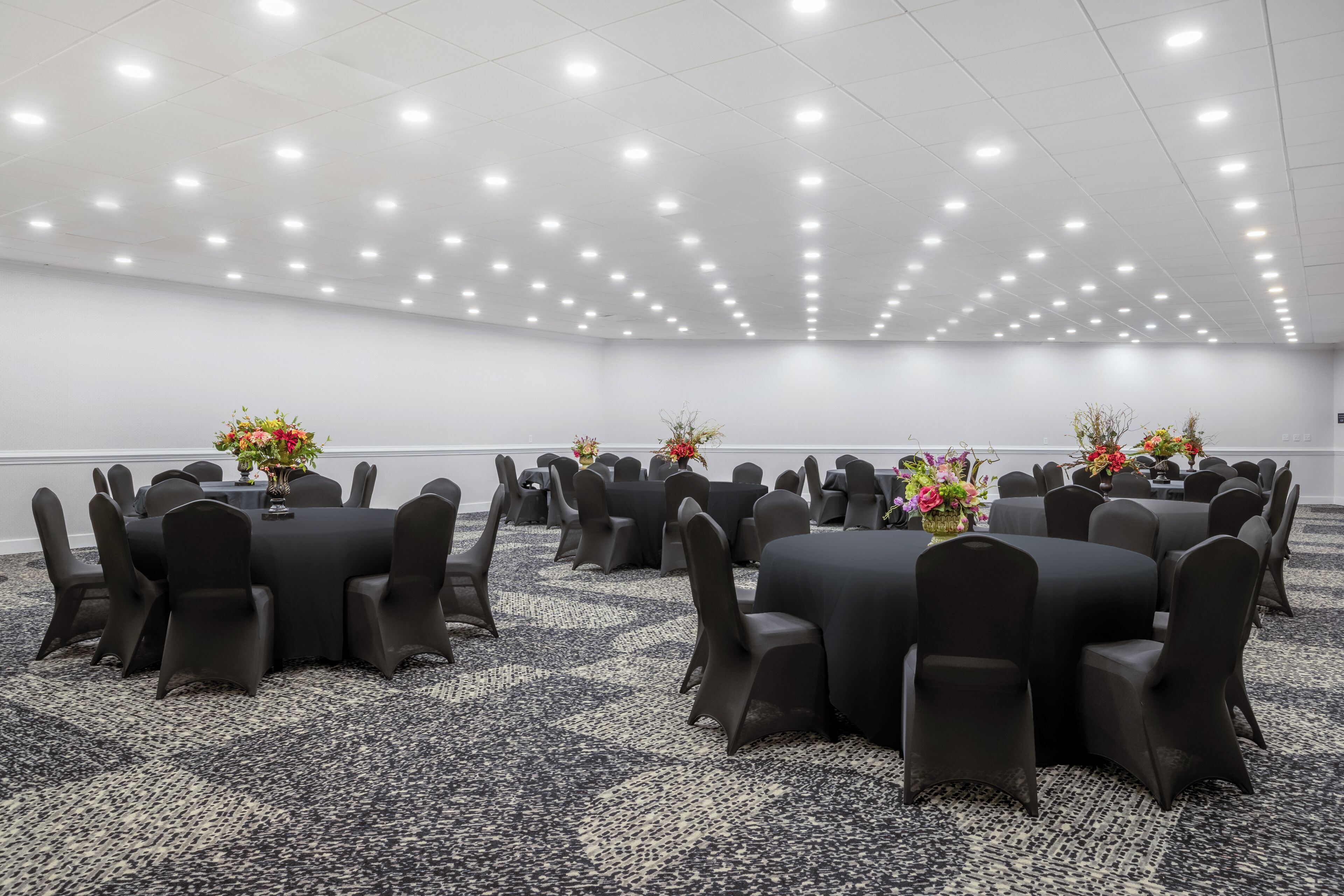 Un salón de conferencias con varias mesas y sillas dispuestas en forma de cuadrícula.