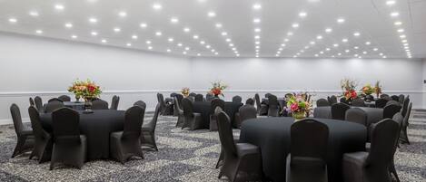 Un salón de conferencias con varias mesas y sillas dispuestas en forma de cuadrícula.