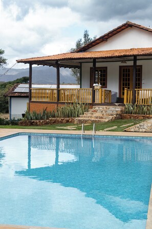 A swimming pool with a house in the background. - Pousada Canto Verde Cipó (Jaboticatubas)