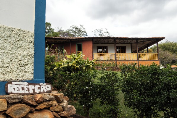 A building with a reception area, a balcony, and a garden. - Pousada Canto Verde Cipó (Jaboticatubas)