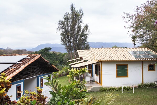 A white house with a tiled roof, a small patio, and a view of mountains in the background.