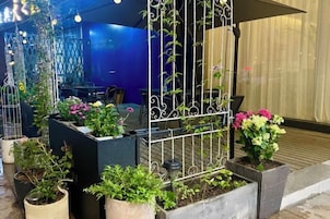 Un patio con plantas en macetas y una valla de metal.