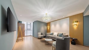 Un salon moderne comprenant un canapé, des fauteuils, une table basse, un téléviseur et un lustre.