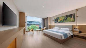 Une chambre d’hôtel moderne dotée d’un grand lit, d’un téléviseur à écran plat, d’un tableau et offrant une vue sur la ville.