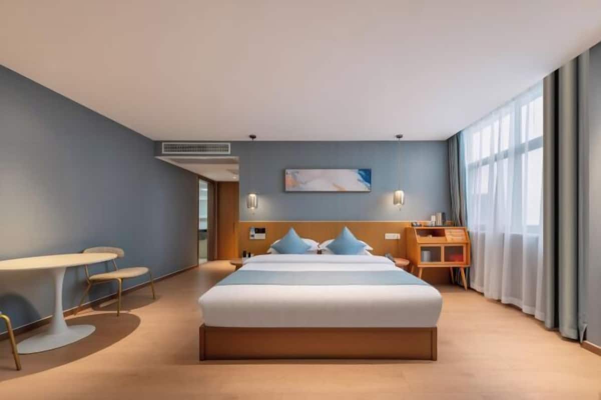 Quarto de hotel moderno com uma cama grande, uma mesa e uma cadeira.