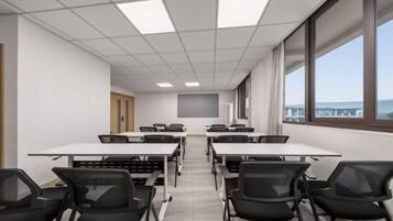 A conference room with tables and chairs, large windows, and a view of the outside.