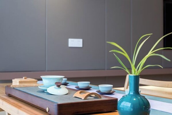 A wooden tray with tea set and a vase with green leaves.