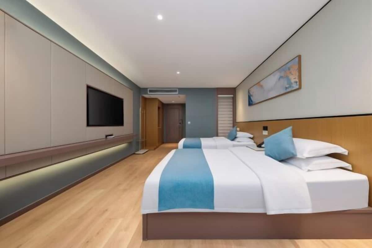 Quarto de hotel moderno com uma cama grande, televisão de tela plana e um quadro na parede.