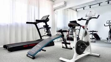 A gym with exercise equipment including treadmills, a stationary bike, and a weight bench.