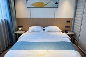 A hotel room with a bed, a bedside table, a lamp, and a painting on the wall.