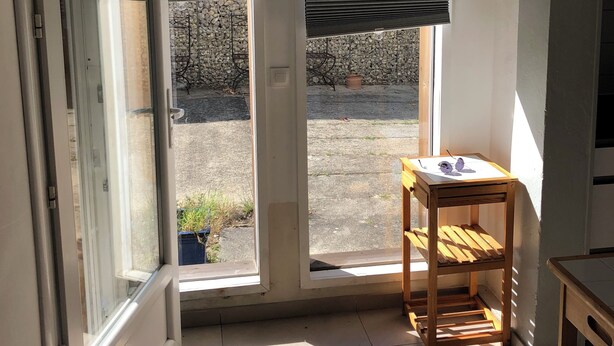 A room with two windows, a wooden table, and a ceiling light fixture. - Maison Fond de Jardin Située à 100 m de la Plage. 2 Chambres Pour 7 Personnes (Mimizan)