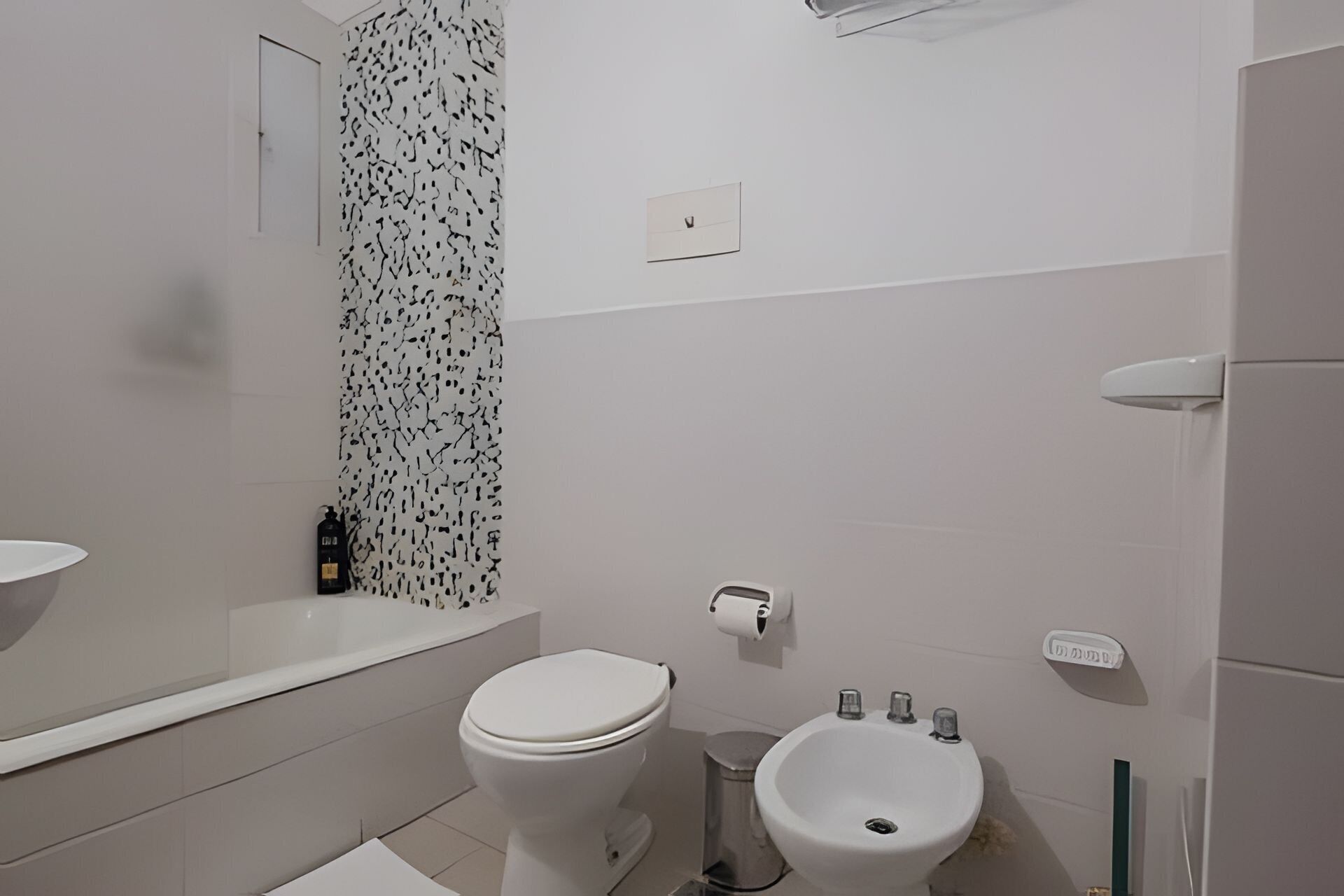 Ein Badezimmer mit Toilette, Bidet, Waschbecken und Duschbereich.