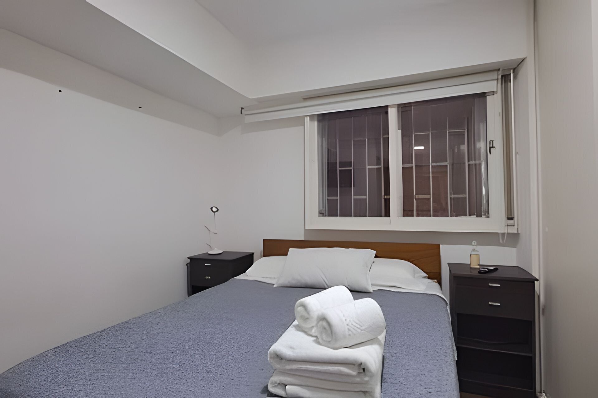 A bedroom with a bed, a window, a nightstand, and a dresser.