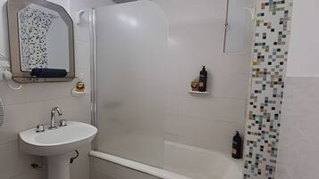 A bathroom with a white sink, a shower with a glass door, and a tiled shower curtain.