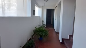 A corridor with a potted plant, a staircase, and a door at the end. - Hornera Rodi - Strategic location, parking, and pool (Rosario)
