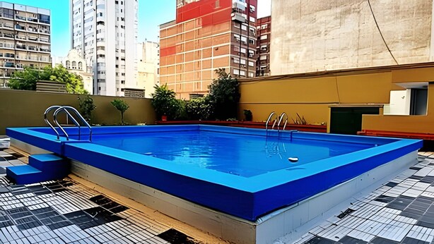 A rectangular swimming pool with blue tiles and metal ladders, surrounded by a tiled deck. - Hornera Rodi - Strategic location, parking, and pool (Rosario)