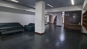 A spacious lobby with a black floor, a reception desk, a staircase, and a seating area with two chairs. - Hornera Rodi - Strategic location, parking, and pool (Rosario)