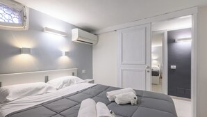 Et moderne hotelværelse med en stor seng, to sengeborde med lamper, en klimaanlæg og et garderobeskab med spejl.