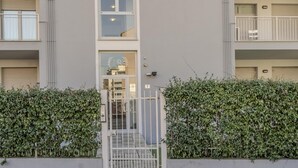 Un immeuble d’appartements moderne, doté d’une entrée sécurisée par un portail, d’un balcon bien visible et d’une haie bien entretenue.