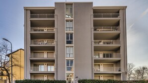 Un immeuble résidentiel à plusieurs étages, doté de balcons, d’une entrée centrale et d’une façade uniforme.