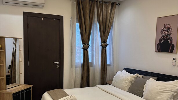 Quarto moderno com cama de madeira, guarda-roupa, ar condicionado e um quadro na parede.