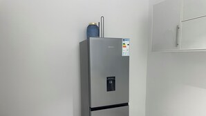 Uma cozinha compacta e moderna, com geladeira embutida, dispensador de água e um armário pequeno.