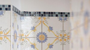 A bathroom with decorative tiles featuring floral patterns and a white towel hanging on a rack. - Ischia Mare (Forio)