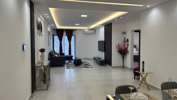 Un salon moderne avec un canapé, un téléviseur et un coin repas avec une table mise pour deux personnes.